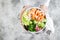 Girl holding shrimp poke bowl with seaweed, avocado, cucumber, radish, sesame seeds