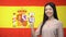 Girl holding smartphone with language study app, Spanish flag on background