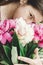 Girl holding and smelling beautiful pink and white peonies bouquet at rustic old wooden window. Floral decor and arrangement.