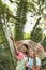 Girl Holding Umbrella With Friend Pointing In Forest