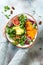 Girl holding vegan, detox Buddha bowl with turmeric roasted chickpeas, greens, avocado, persimmon, blood orange, nuts