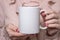 Girl is holding white cup in hands. White mug for woman, gift. Mockup for designs