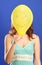 Girl holding yellow smiling balloon close up