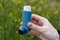 A girl holds an asthma inhaler against a background of blooming