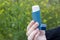 A girl holds an asthma inhaler against a background of blooming