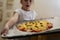 The girl holds on a baking sheet prepared for baking pizza with beef. Cooking.