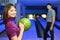 Girl holds ball for bowling and man look at it