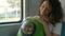 Girl holds cat in backpack with porthole traveling by train