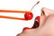 Girl holds chopsticks a red sweet cherry near lips
