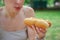 Girl holds a classic hotdog with ketchup and fried onions in her hand.