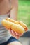 Girl holds a classic hotdog with ketchup and fried onions in her hand.