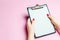 The girl holds an empty tablet for records on a pink background. The concept of control and inventory. Records and work process.