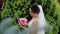 The girl holds fresh flowers in her hands and turns her head to smile at the camera.