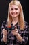 A girl holds a game joystick and smiles shudderingly. On a black background.