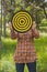 Girl holds in the hands dartboard with arrow in the center target outside in the park