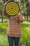 Girl holds in the hands dartboard with arrow in the center target outside in the park