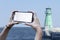 Girl holds in his hand a smartphone close-up, with a white screen on a background of sea. Mock-up Technology