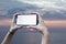 Girl holds in his hand a smartphone close-up, with a white screen on a background of sea. Mock-up Technology