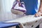 The girl holds an iron on an ironing board with a ferry and irons things. Cleaning service of the apartment. Blue T-shirt. macro