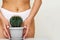 The girl holds a large cactus in the groin or bikini area. The concept of intimate hygiene, epilation and depilation