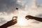 Girl holds out plastic bottle with crystal clear mineral water to woman. Two hands opposite the rays of the sunset sky. Concept.