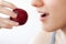 The girl holds a plum in her hand in front of her wide open mouth