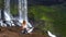 Girl holds pranayama yoga pose on large rock at waterfall