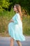 Girl holds a pregnant belly. Pregnant woman against the backdrop of nature, warm weather