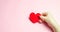 The girl holds a red heart in hands. Valentine`s day concept. Love and romance. Holiday. Minimalism. Romantic composition. Health