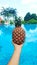 Girl holds ripe pineapple fruit on a background of a pool with blue water. Luxury holidays in the tropics