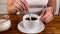 Girl holds a spoon and strews sugar to mug