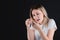 Girl holds on to a bruised finger, on a black isolated background, emotional portrait