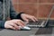 The girl holds a white wire-free computer mouse and prints text on a laptop at home at the computer. gray jacket. The girl works