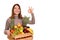 Girl holds wooden crate with fruits and shows ok hand sign