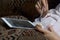 A girl in a home bathrobe lying on the couch working with a tablet. At the same time he eats yogurt.