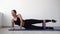 a girl at home using elastic rubber trains her lower muscles lying on the mat, a determined athlete reaching fitness