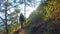 Girl in a hood and carrying a backpack walks along a steep slope on a sunny day