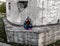 A girl in a hood sits in a lotus pose on a concrete wall