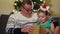 A girl in a hoop with a Santa hat hugs her grandfather and thanks him for the gift. Family Christmas Eve