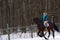 A girl on a horse jumps gallops. A girl trains riding a horse in a small paddock. A cloudy winter day