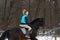 A girl on a horse jumps gallops. A girl trains riding a horse in a small paddock. A cloudy winter day