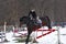 A girl on a horse jumps over the barrier. Training girl jockey riding a horse. A cloudy winter day