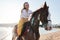 Girl horseback rider sitting on a horse stroking horse`s neck