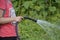 A girl is hosing down the garden.