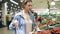 The girl, housewife shopping at the supermarket. Chooses fresh tomatoes on a branch, puts them in a cellophane bag, ties