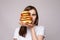 Girl with huge hamburger on hand.Studio portrait of young brunette woman in white t-shirt holding enormous burgers on