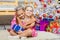 Girl hugging another girl sitting on a mat at the Christmas tree