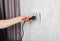 The girl incorrectly removes the electric plug from the socket and breaks the socket. Danger of electric shock, close-up