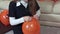 Girl inflates a orange hallowen balloon, tieing it.
