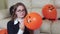 Girl inflates a orange hallowen balloon, tieing it.